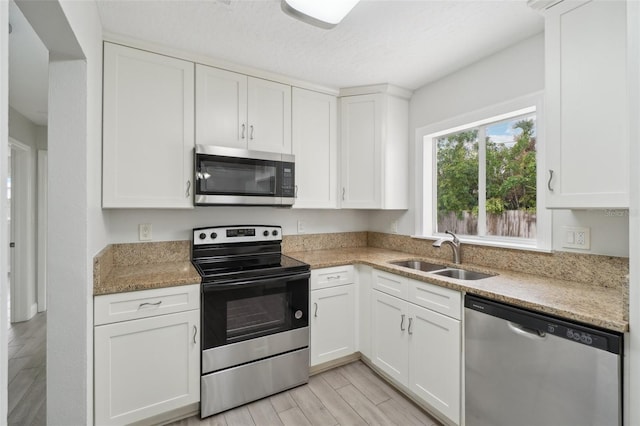 kitchen featuring white cabinets, appliances with stainless steel finishes, stone countertops, and sink