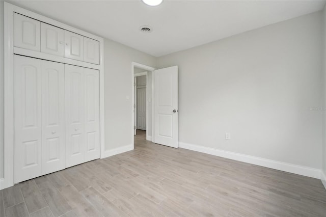 unfurnished bedroom featuring light hardwood / wood-style flooring and a closet