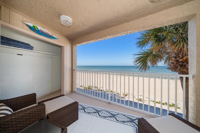 balcony featuring a water view and a beach view