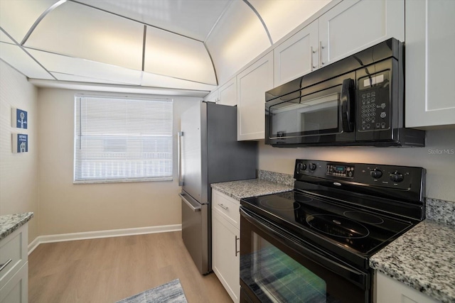 kitchen featuring light wood-type flooring, white cabinets, light stone counters, and black appliances