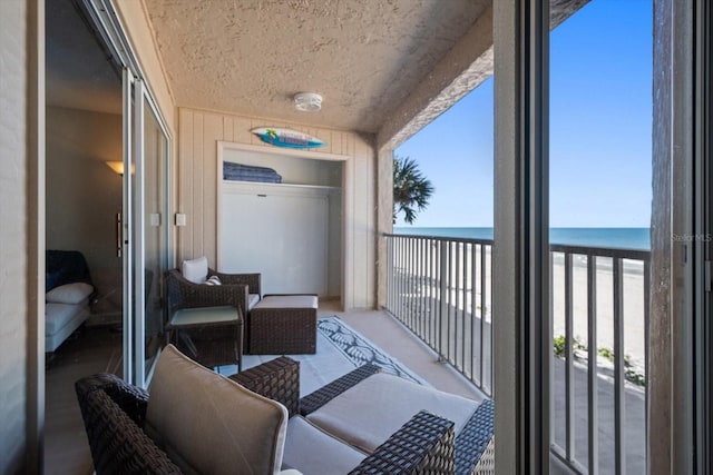 balcony featuring a water view and a beach view