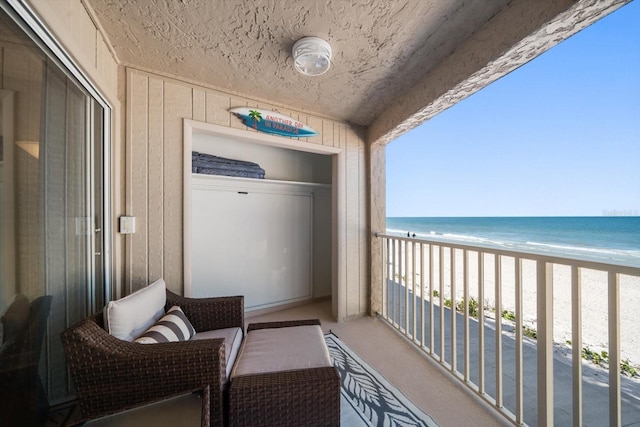 balcony featuring a beach view and a water view