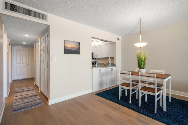 dining space featuring wood-type flooring and a textured ceiling