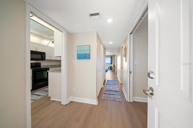 hall with light hardwood / wood-style flooring and a textured ceiling