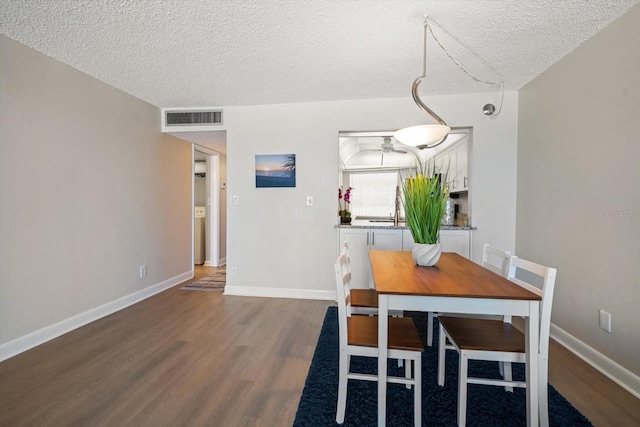 dining room featuring dark wood-type flooring and a textured ceiling