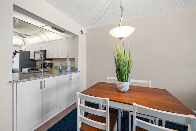 kitchen with hanging light fixtures, white cabinetry, appliances with stainless steel finishes, and a textured ceiling