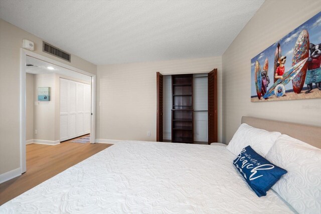 bedroom featuring hardwood / wood-style floors, a textured ceiling, and a closet