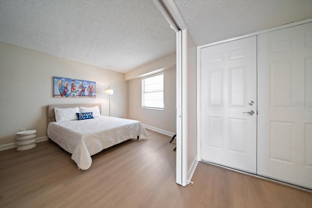 bedroom with wood-type flooring, a textured ceiling, and a closet