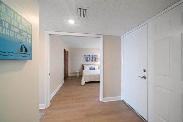 hall featuring a textured ceiling and light wood-type flooring