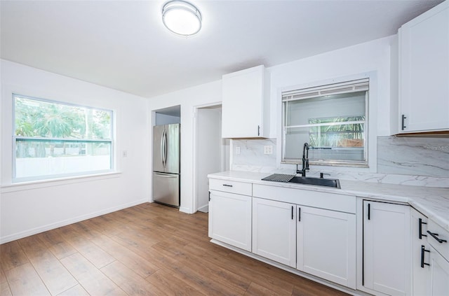 kitchen featuring stainless steel refrigerator, white cabinetry, sink, and decorative backsplash