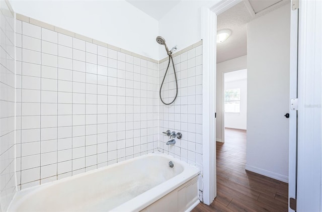 bathroom featuring hardwood / wood-style flooring, a textured ceiling, and tiled shower / bath