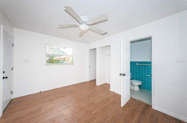 unfurnished bedroom with a closet, ceiling fan, hardwood / wood-style floors, and ensuite bathroom