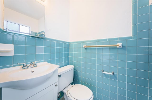 bathroom with vanity, toilet, and tile walls