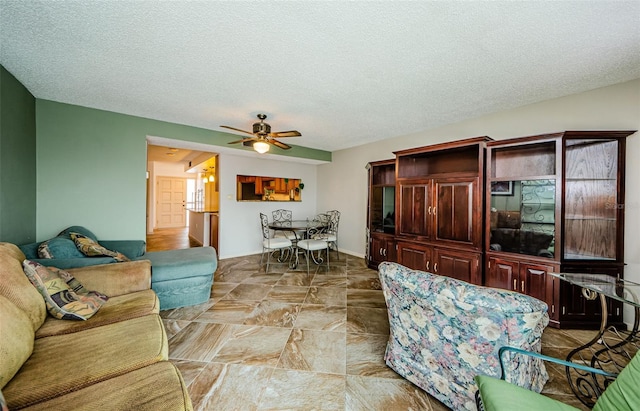 living room with ceiling fan and a textured ceiling