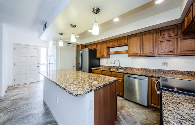 kitchen with appliances with stainless steel finishes, sink, stone counters, a center island, and hanging light fixtures