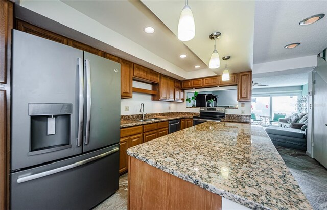 kitchen featuring ceiling fan, sink, hanging light fixtures, stainless steel appliances, and light stone counters