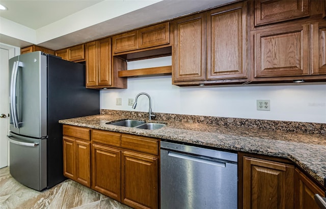 kitchen featuring dark stone countertops, sink, and stainless steel appliances