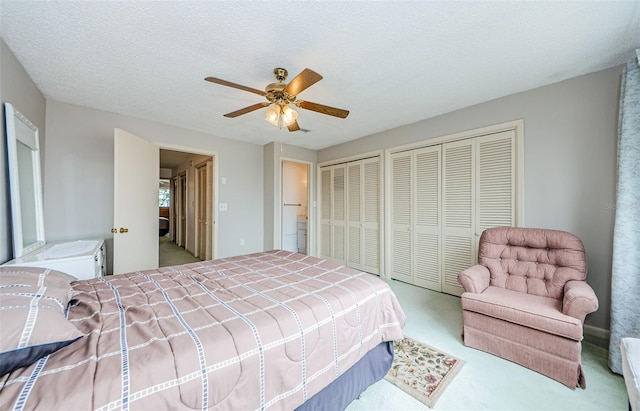 carpeted bedroom featuring a textured ceiling, ceiling fan, and multiple closets