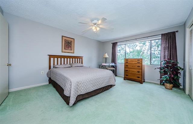 carpeted bedroom featuring ceiling fan, a textured ceiling, and a closet