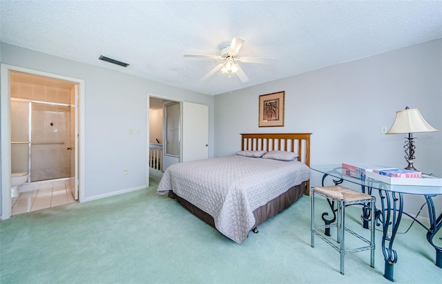 carpeted bedroom with ensuite bath, ceiling fan, and a textured ceiling