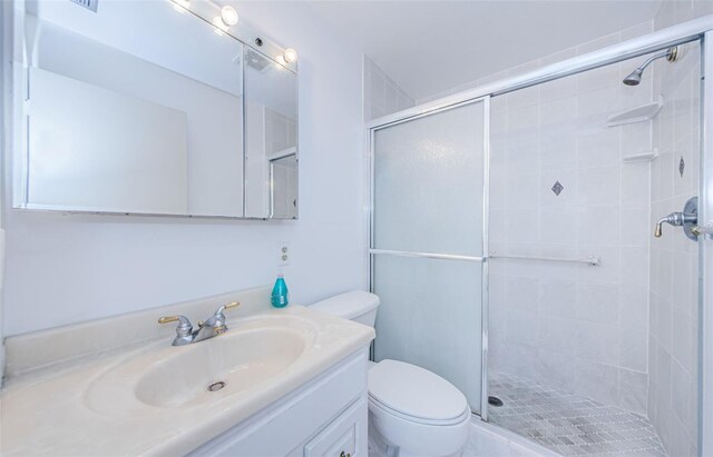 bathroom featuring vanity, a shower with shower door, and toilet