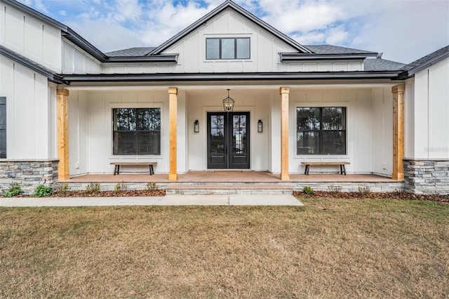 doorway to property featuring a yard, french doors, and a porch