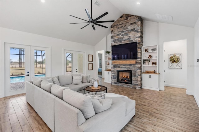 living room with ceiling fan, a stone fireplace, and high vaulted ceiling