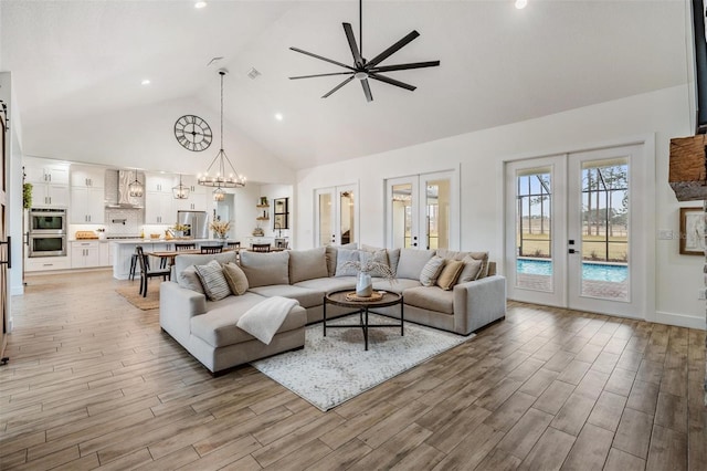 living room with french doors, high vaulted ceiling, and ceiling fan with notable chandelier