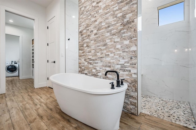 bathroom featuring washer / dryer and plus walk in shower