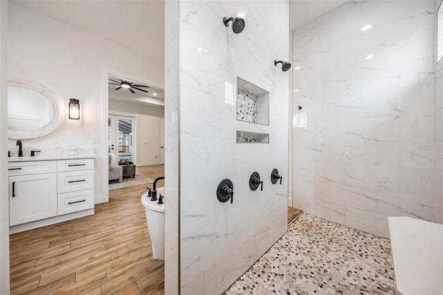 bathroom with ceiling fan, tiled shower, and vanity