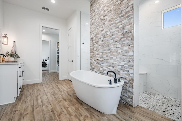 bathroom featuring vanity, independent shower and bath, and washer / dryer