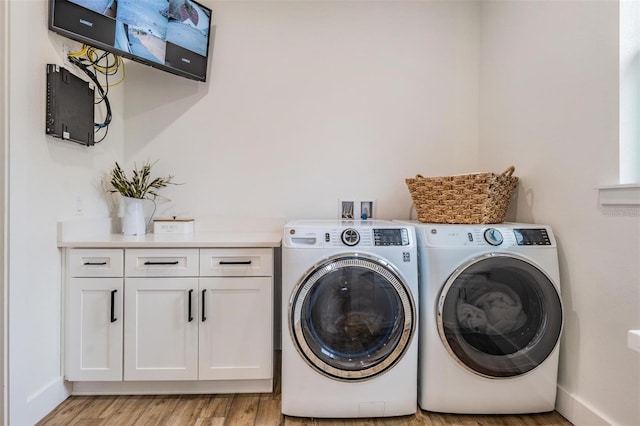 laundry area with washer and clothes dryer, light hardwood / wood-style floors, and cabinets