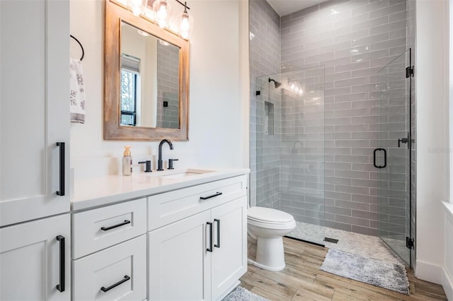 bathroom with walk in shower, toilet, vanity, and hardwood / wood-style flooring