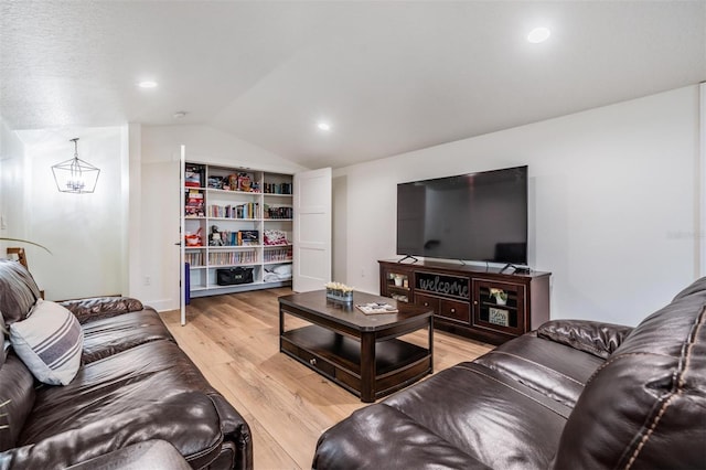 living room with lofted ceiling, a notable chandelier, and light wood-type flooring