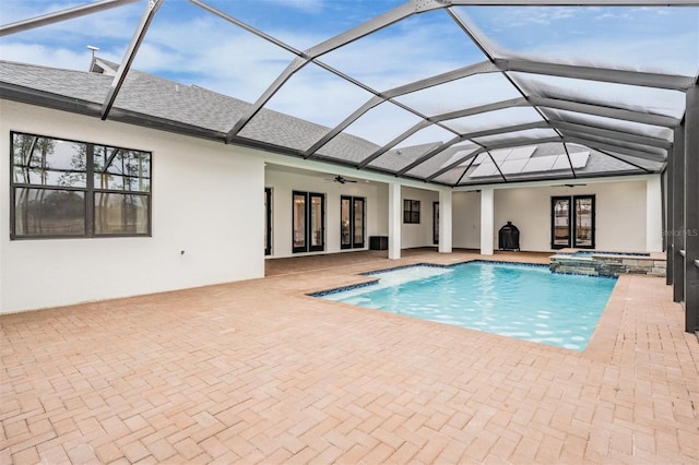 view of swimming pool with an in ground hot tub, french doors, ceiling fan, glass enclosure, and a patio