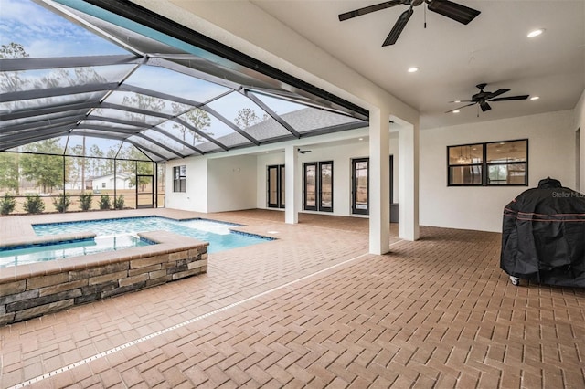 view of pool featuring glass enclosure, ceiling fan, grilling area, a patio area, and an in ground hot tub