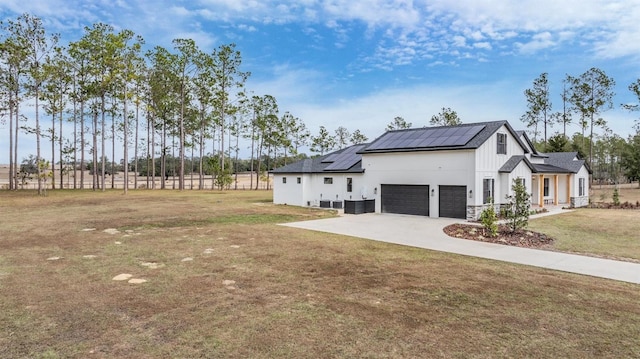 view of side of property with solar panels, a yard, a garage, and central air condition unit