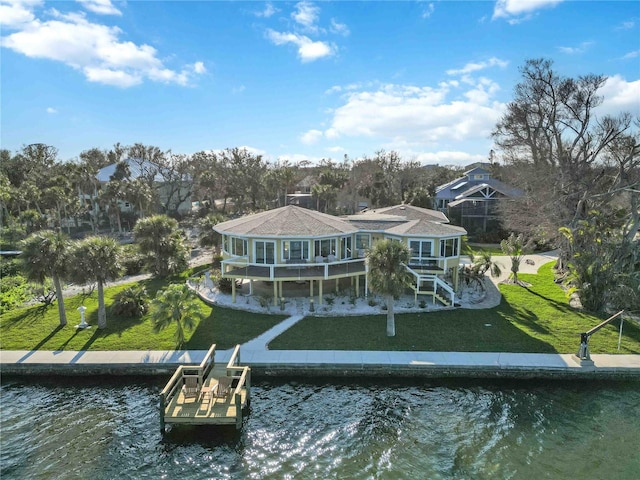 rear view of house with a water view and a lawn