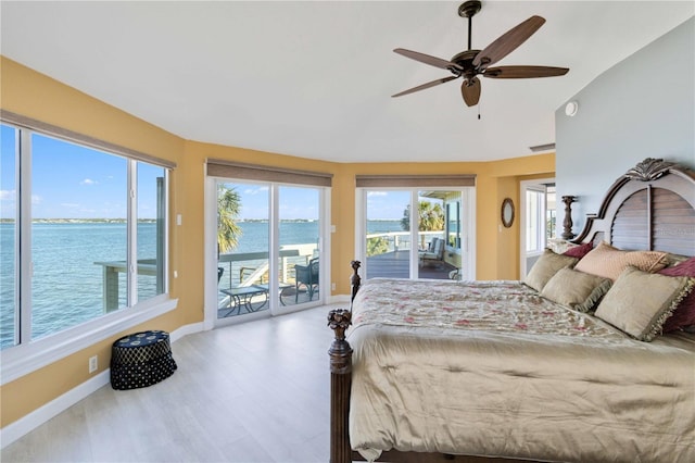 bedroom featuring a water view, access to outside, multiple windows, and ceiling fan