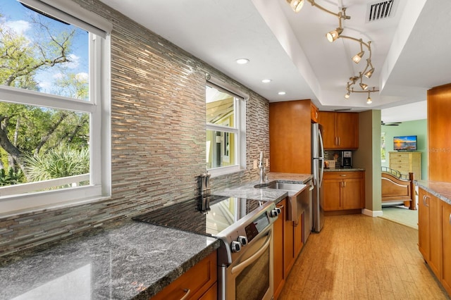 kitchen featuring stainless steel appliances, dark stone countertops, backsplash, and sink