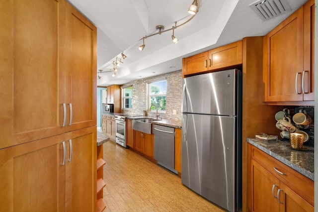 kitchen featuring sink, decorative backsplash, appliances with stainless steel finishes, and dark stone countertops