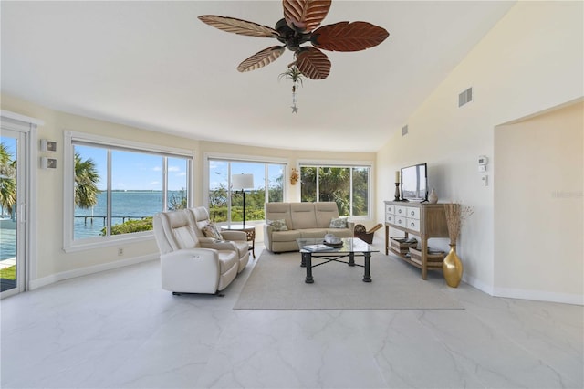 living room featuring ceiling fan, vaulted ceiling, a water view, and a healthy amount of sunlight