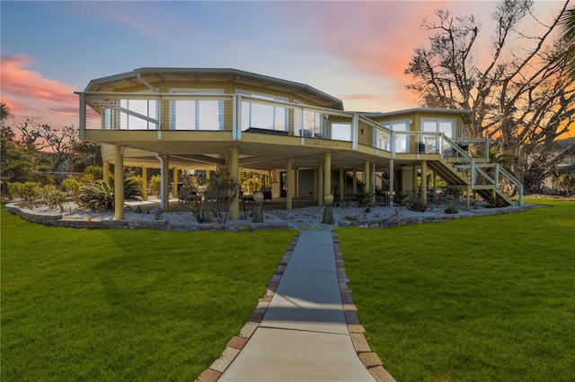 back house at dusk featuring a wooden deck and a yard