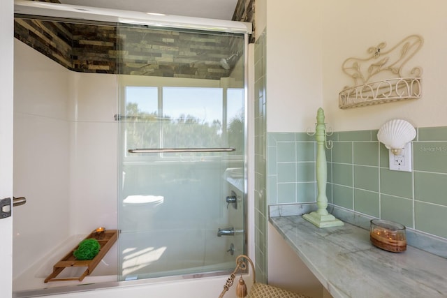 bathroom with combined bath / shower with glass door and tile walls