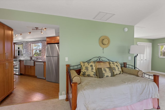 bedroom with light wood-type flooring, sink, and stainless steel refrigerator