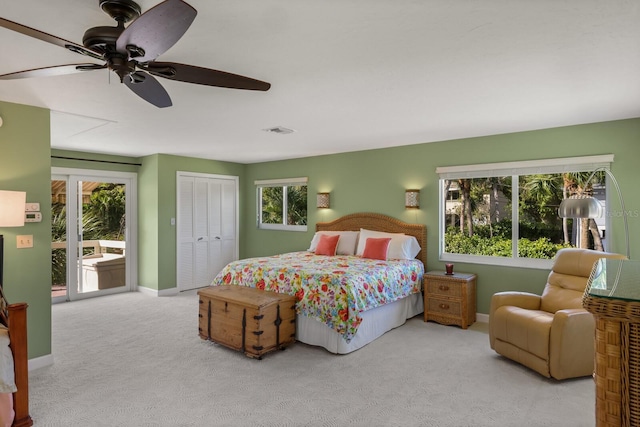 bedroom with ceiling fan, access to exterior, light colored carpet, and a closet