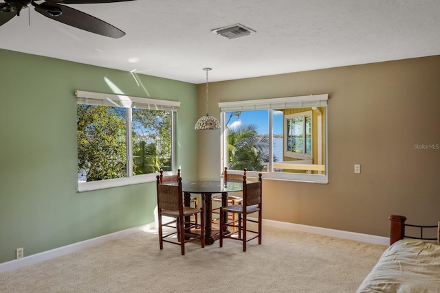 carpeted dining room with ceiling fan