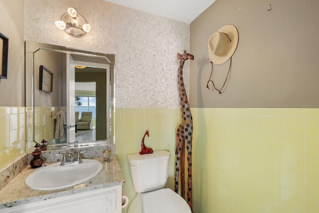 bathroom featuring tile walls, toilet, and vanity