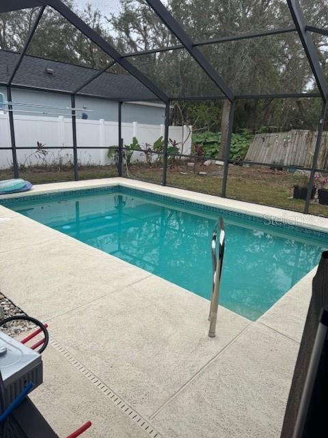 view of swimming pool featuring glass enclosure and a patio