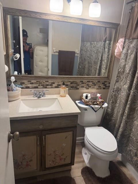 bathroom with vanity, toilet, decorative backsplash, and hardwood / wood-style flooring